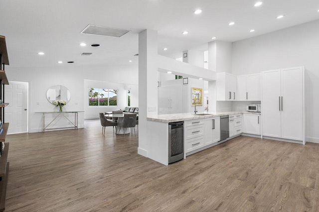 kitchen with white cabinets, kitchen peninsula, hardwood / wood-style floors, and wine cooler