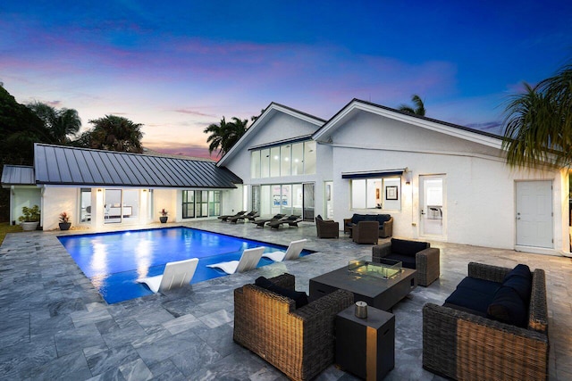 pool at dusk featuring outdoor lounge area and a patio