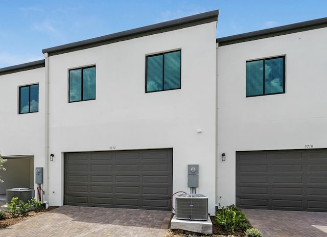 exterior space with central AC unit and a garage