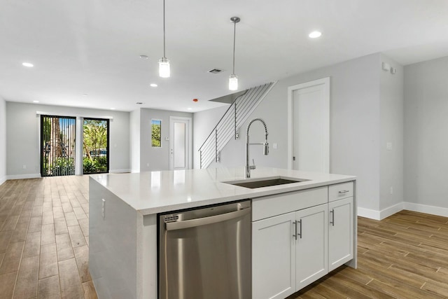 kitchen featuring white cabinetry, sink, stainless steel dishwasher, and light hardwood / wood-style flooring