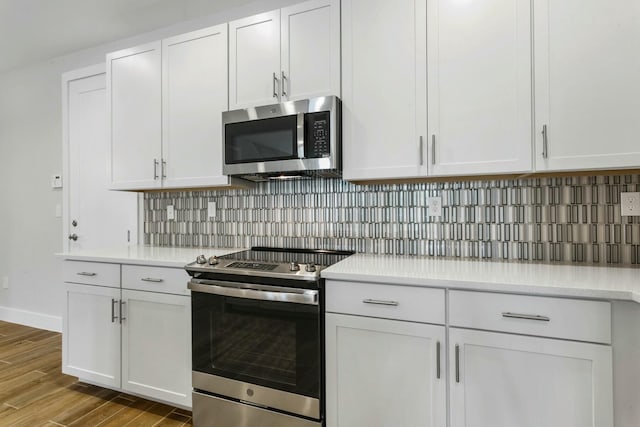 kitchen with decorative backsplash, white cabinetry, stainless steel appliances, and light wood-type flooring