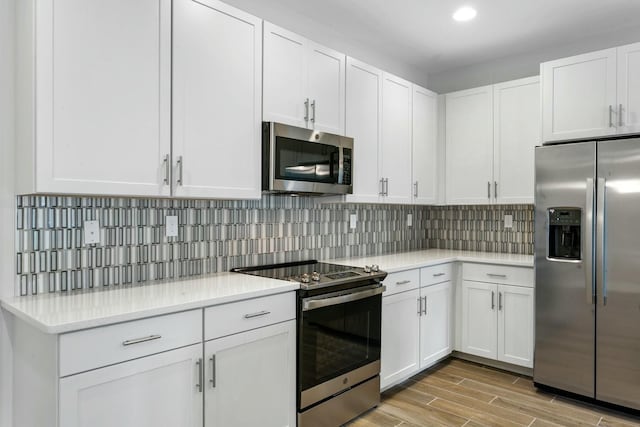 kitchen featuring decorative backsplash, appliances with stainless steel finishes, light hardwood / wood-style flooring, and white cabinetry