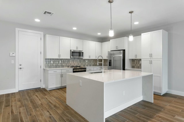 kitchen featuring white cabinetry, sink, dark hardwood / wood-style floors, an island with sink, and appliances with stainless steel finishes