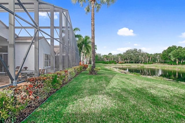 view of yard with a lanai and a water view