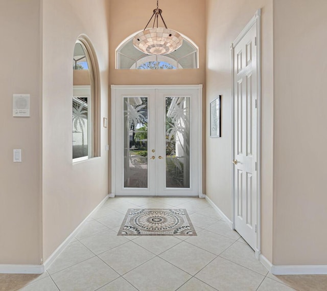 tiled foyer entrance with a notable chandelier and french doors