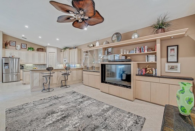 kitchen with stainless steel refrigerator with ice dispenser, a kitchen breakfast bar, tasteful backsplash, a center island, and lofted ceiling