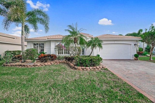 mediterranean / spanish house featuring a garage and a front lawn