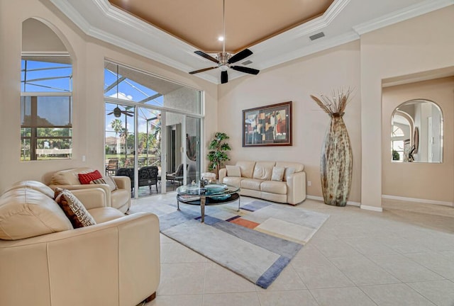 tiled living room with a tray ceiling, ceiling fan, and ornamental molding