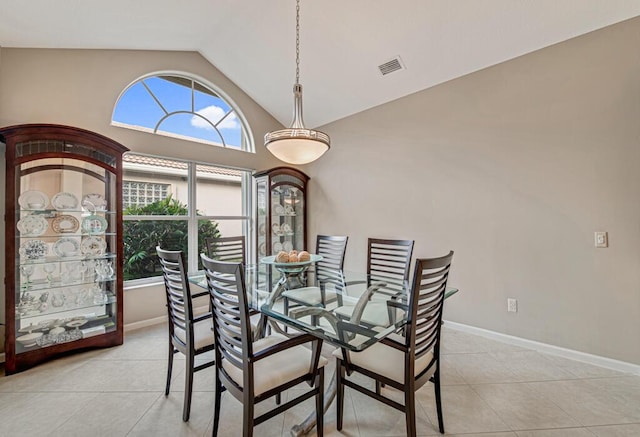 dining room with light tile patterned floors and vaulted ceiling