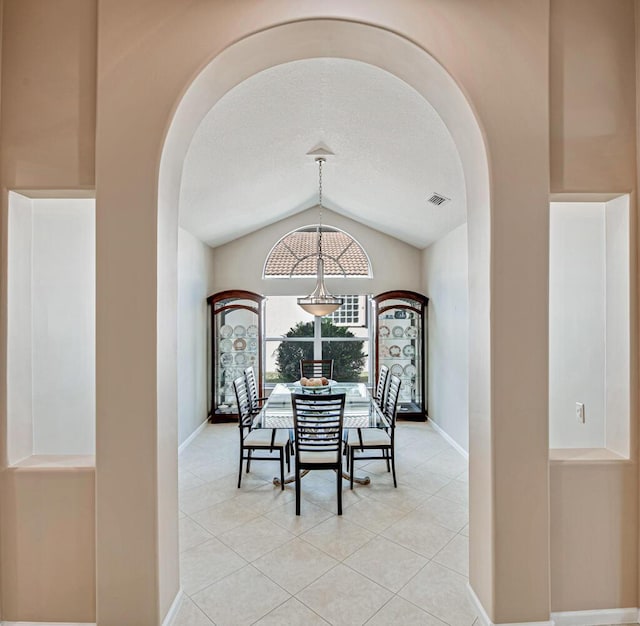 tiled dining area with lofted ceiling and a textured ceiling