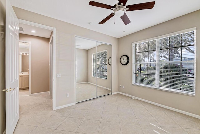 unfurnished bedroom featuring multiple windows, ceiling fan, a closet, and light tile patterned flooring