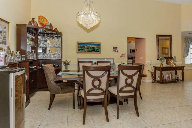 dining space featuring light tile patterned flooring, beverage cooler, a high ceiling, and a notable chandelier