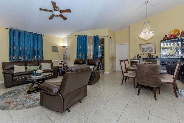 living room with lofted ceiling, ceiling fan with notable chandelier, and light tile patterned floors