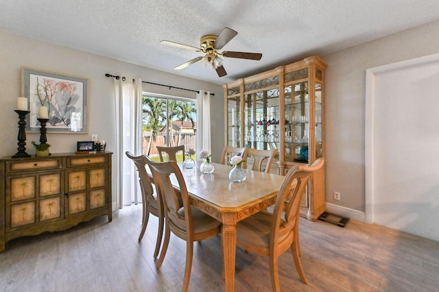 dining area featuring ceiling fan, wood-type flooring, and a textured ceiling