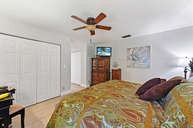 bedroom with ceiling fan, light hardwood / wood-style floors, and a textured ceiling