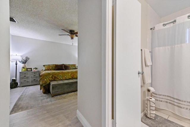 bathroom featuring wood-type flooring, a textured ceiling, and ceiling fan