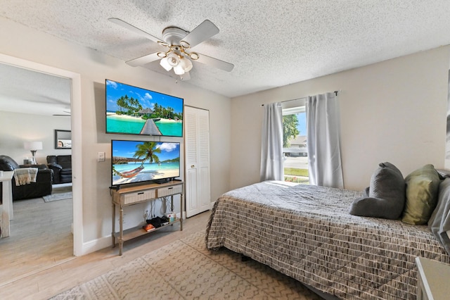 bedroom with ceiling fan, light wood-type flooring, a textured ceiling, and a closet