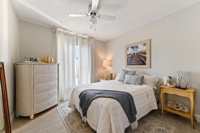 bedroom with ceiling fan, a textured ceiling, and hardwood / wood-style flooring