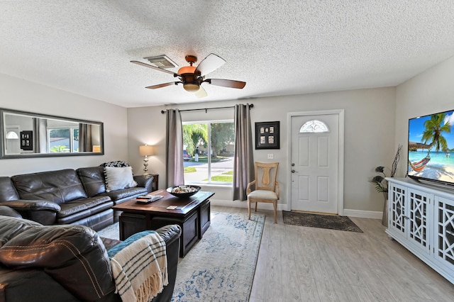 living room with light wood-type flooring, a textured ceiling, and ceiling fan