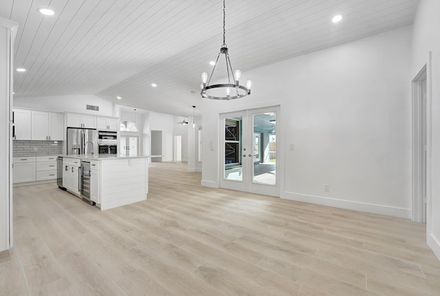 kitchen featuring lofted ceiling, a center island with sink, hanging light fixtures, appliances with stainless steel finishes, and light hardwood / wood-style floors