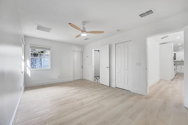 unfurnished bedroom with light wood-type flooring, ceiling fan, and multiple closets