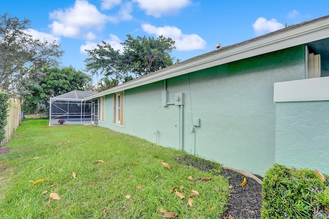 view of side of property featuring a lanai and a lawn