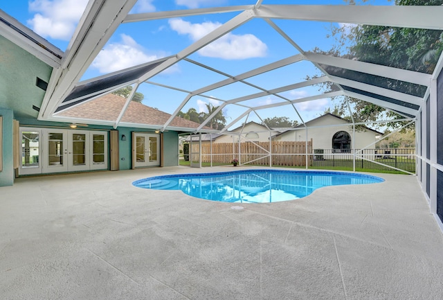 view of swimming pool featuring glass enclosure, a patio area, and french doors