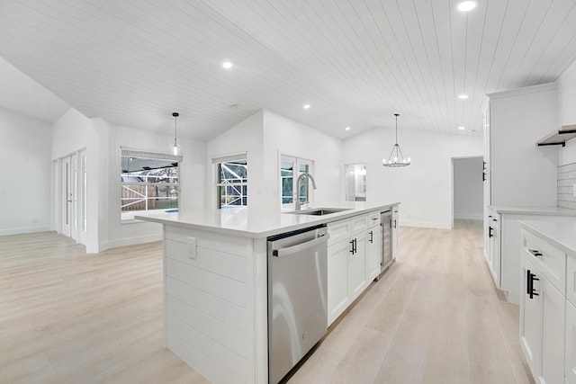 kitchen featuring dishwasher, sink, hanging light fixtures, vaulted ceiling, and an island with sink