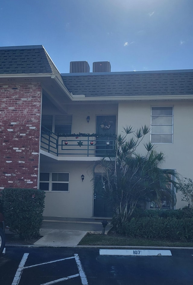 view of exterior entry with cooling unit and a balcony