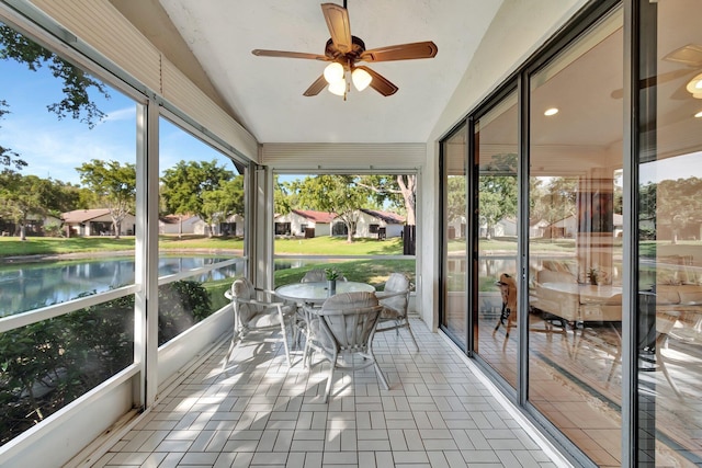 unfurnished sunroom with ceiling fan, plenty of natural light, a water view, and vaulted ceiling