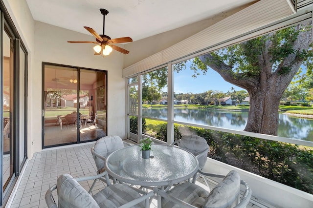 sunroom featuring ceiling fan, a water view, and vaulted ceiling