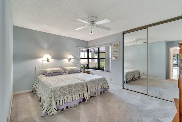 bedroom featuring ceiling fan, light colored carpet, a textured ceiling, and a closet