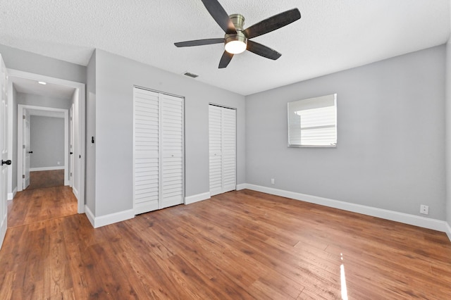 unfurnished bedroom featuring ceiling fan, wood-type flooring, and a textured ceiling