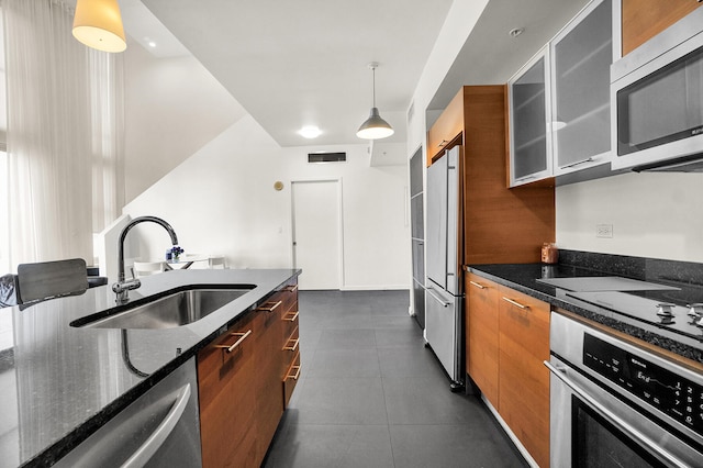 kitchen featuring sink, stainless steel appliances, dark stone countertops, pendant lighting, and dark tile patterned flooring