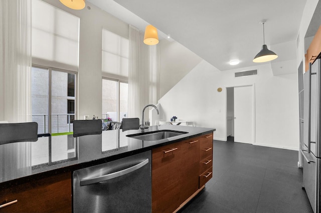 kitchen with pendant lighting, dark stone counters, sink, stainless steel dishwasher, and a wealth of natural light