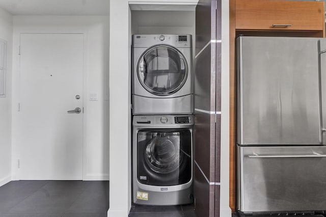 clothes washing area with stacked washer / dryer and dark tile patterned flooring