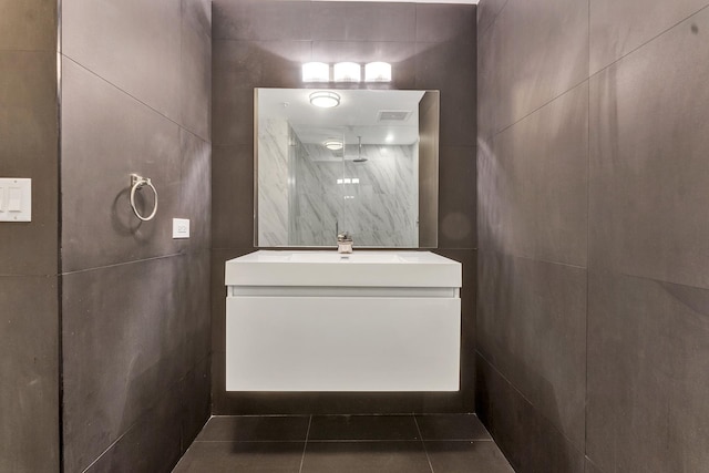 bathroom with tile patterned floors, vanity, tile walls, and walk in shower