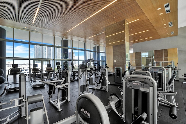 workout area featuring wooden ceiling, a high ceiling, and a wall of windows