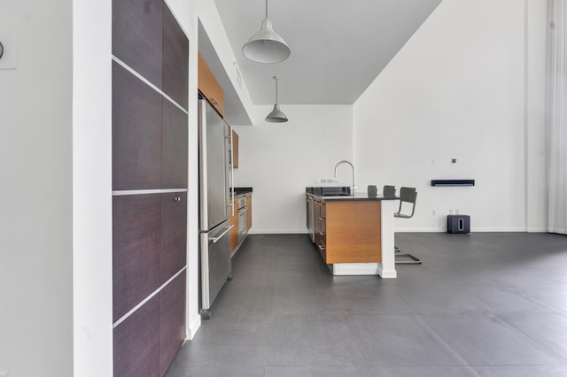 kitchen with a breakfast bar, stainless steel fridge, sink, and decorative light fixtures