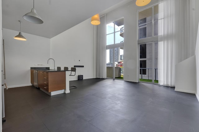 kitchen with dishwasher, a towering ceiling, decorative light fixtures, and sink