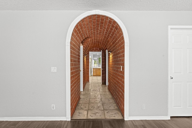 hall featuring hardwood / wood-style flooring and brick wall