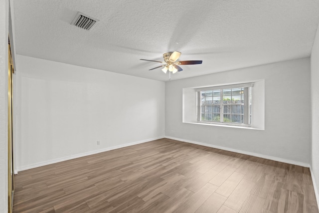 empty room featuring a textured ceiling, hardwood / wood-style flooring, and ceiling fan