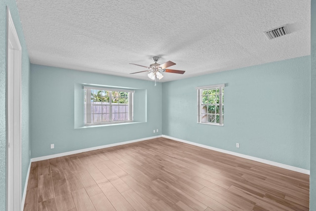 unfurnished room with a wealth of natural light, ceiling fan, a textured ceiling, and hardwood / wood-style flooring