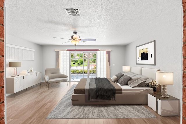 bedroom with ceiling fan, light wood-type flooring, a textured ceiling, and access to outside