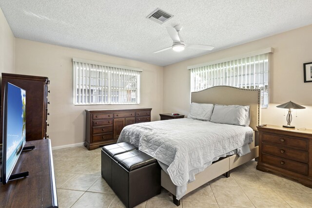 bedroom featuring ceiling fan, light tile patterned flooring, and a textured ceiling