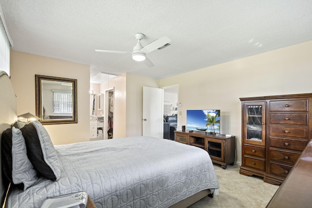 bedroom with ceiling fan, a textured ceiling, and ensuite bath