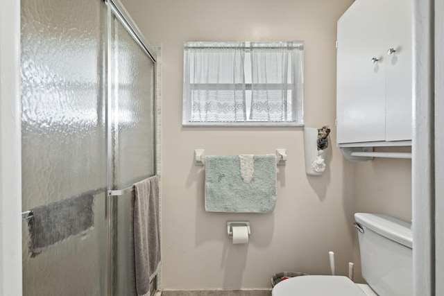 bathroom featuring a shower with shower door and toilet