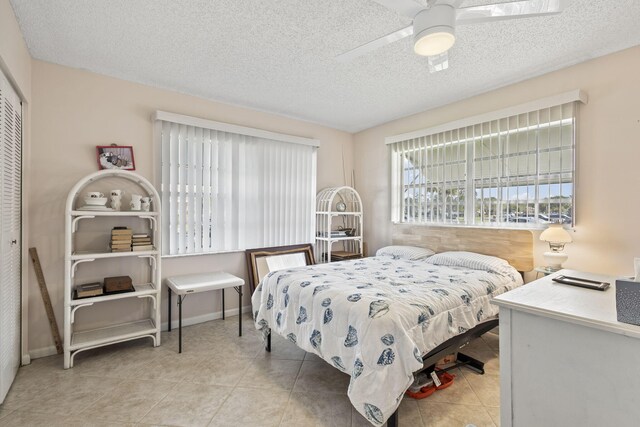 tiled bedroom featuring ceiling fan, a textured ceiling, and a closet