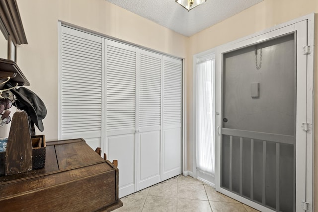 entryway with a textured ceiling and light tile patterned flooring