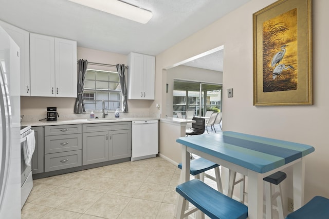 kitchen with gray cabinetry, white appliances, white cabinets, sink, and light tile patterned floors